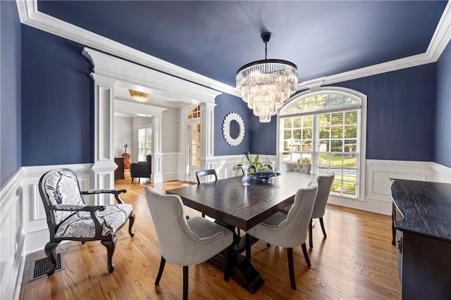 2517 Stone Manor Dr, Buford, GA 30519 - dining area featuring ornate columns, wainscoting, a decorative wall, crown molding, and a chandelier