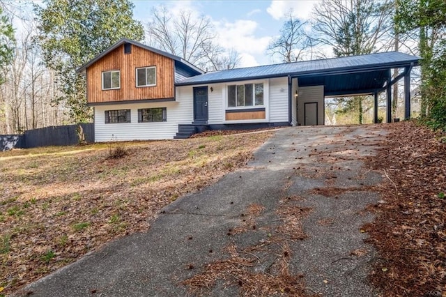 split level home with driveway, fence, metal roof, and a carport