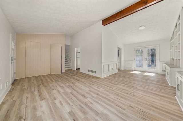 unfurnished living room with vaulted ceiling with beams, visible vents, stairs, french doors, and light wood-type flooring