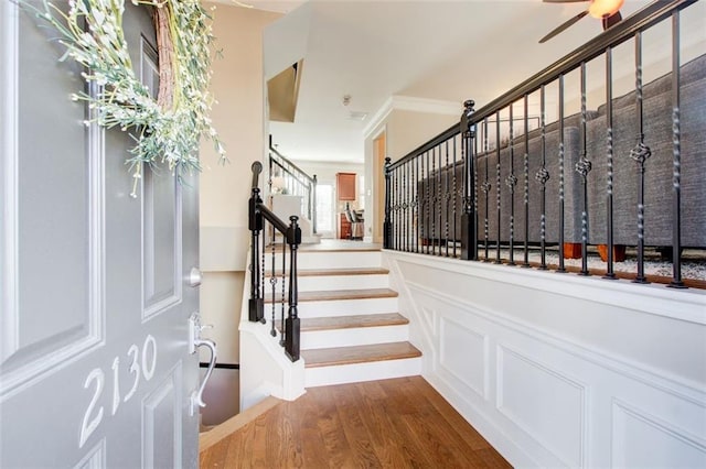 stairway with wood-type flooring and ornamental molding