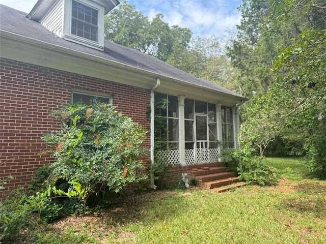 view of side of home with a sunroom and a yard