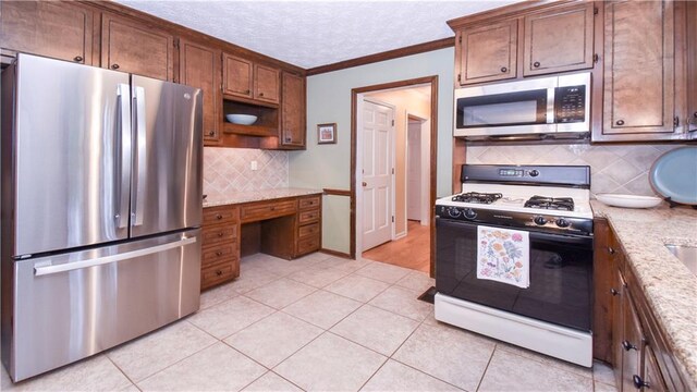 kitchen with light stone counters, crown molding, appliances with stainless steel finishes, and light tile patterned flooring