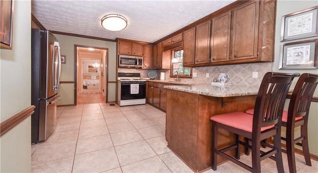 kitchen with kitchen peninsula, light tile patterned floors, backsplash, crown molding, and stainless steel appliances