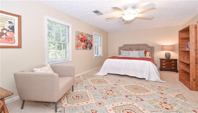 carpeted bedroom with ceiling fan and a textured ceiling