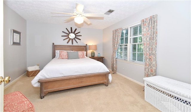 bedroom featuring a textured ceiling, light colored carpet, and ceiling fan