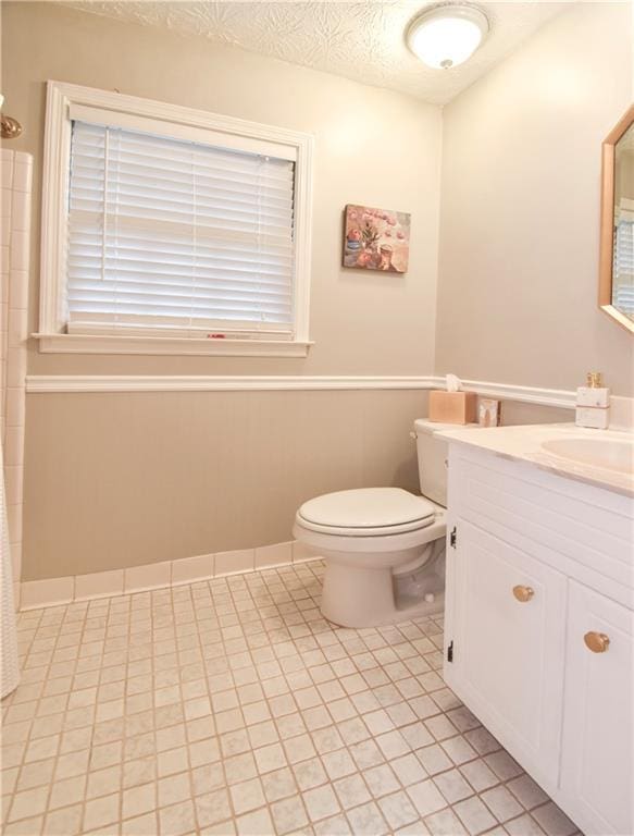 bathroom featuring vanity, toilet, a textured ceiling, and tile patterned flooring