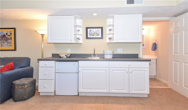 kitchen with sink, white cabinetry, white fridge, and light colored carpet