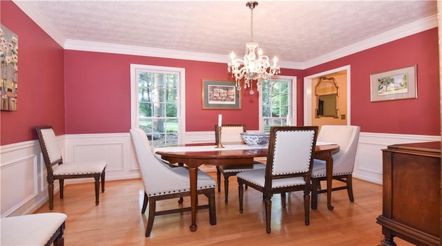 dining room featuring crown molding, a notable chandelier, a textured ceiling, and light wood-type flooring