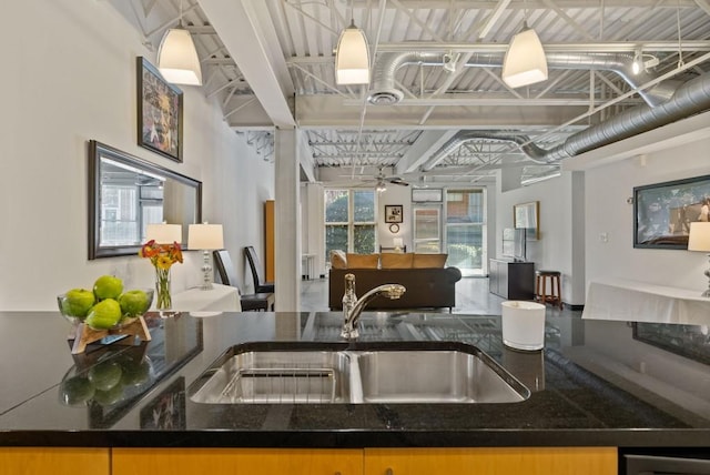 kitchen featuring sink, dark stone counters, hanging light fixtures, and ceiling fan