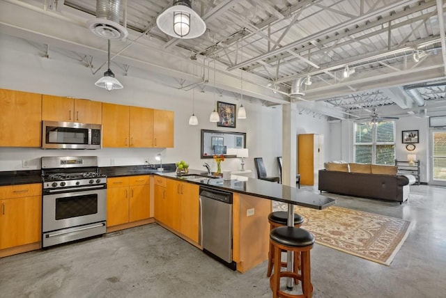 kitchen with a kitchen bar, sink, hanging light fixtures, kitchen peninsula, and stainless steel appliances