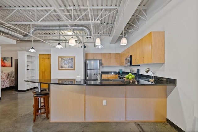 kitchen with appliances with stainless steel finishes, light brown cabinetry, decorative light fixtures, sink, and kitchen peninsula