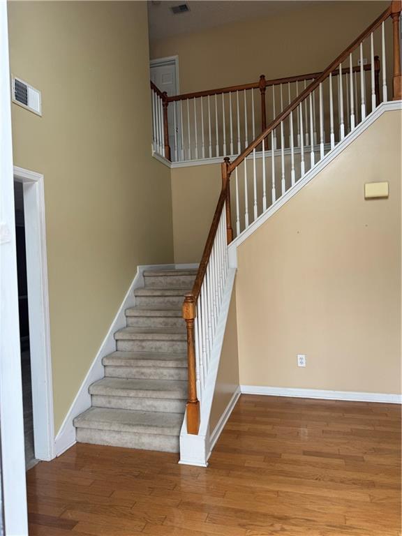 stairway with hardwood / wood-style flooring and a high ceiling