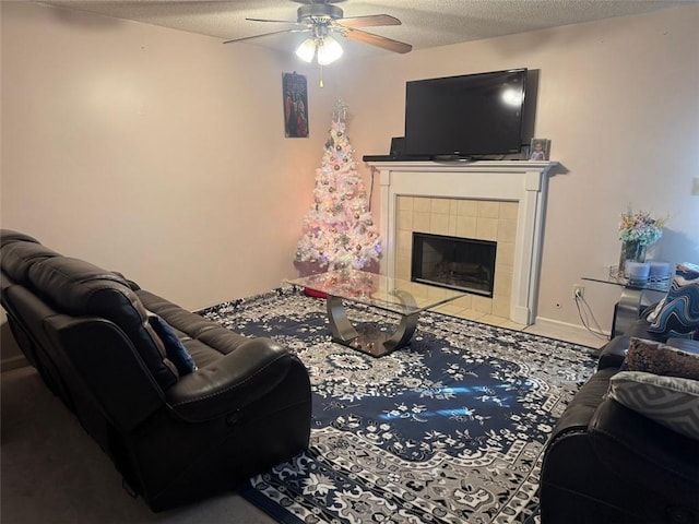 living room with a fireplace, a textured ceiling, and ceiling fan