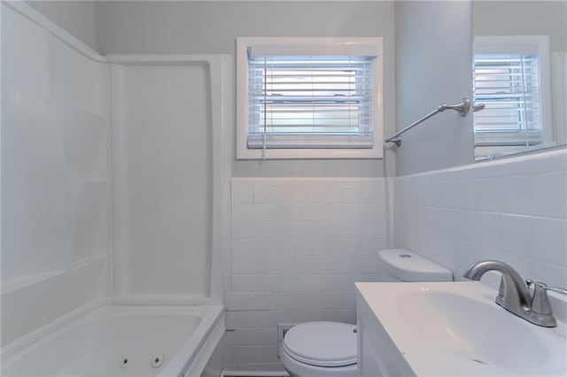 2755 Rockcliff Rd SE, Atlanta, GA 30316 - bathroom with tile walls, toilet, vanity, a combined bath / shower with jetted tub, and a wainscoted wall