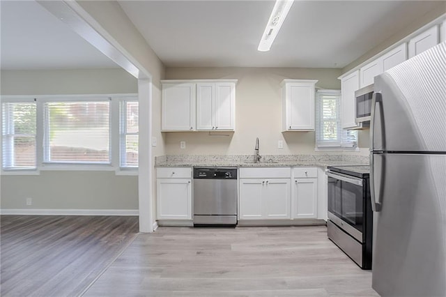 2755 Rockcliff Rd SE, Atlanta, GA 30316 - kitchen with stainless steel appliances, a sink, white cabinetry, light stone countertops, and light wood-type flooring