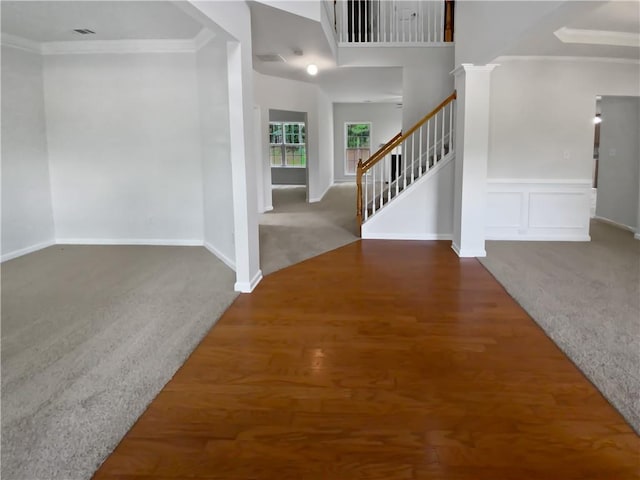 carpeted entryway with ornamental molding and decorative columns