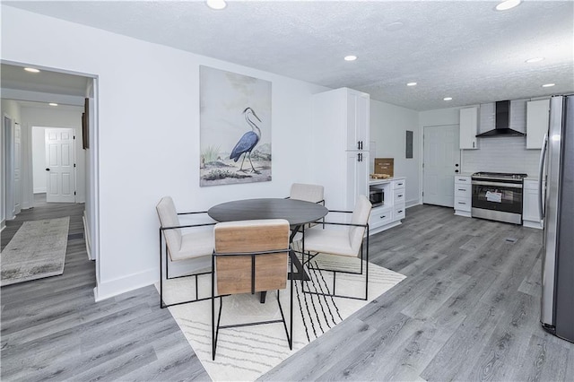 dining space with a textured ceiling, recessed lighting, baseboards, light wood-style floors, and electric panel