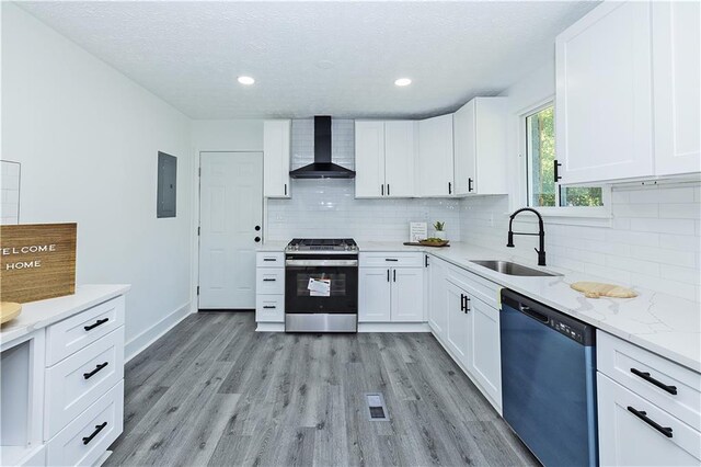 kitchen with dishwashing machine, a sink, light wood-style floors, wall chimney range hood, and stainless steel electric range