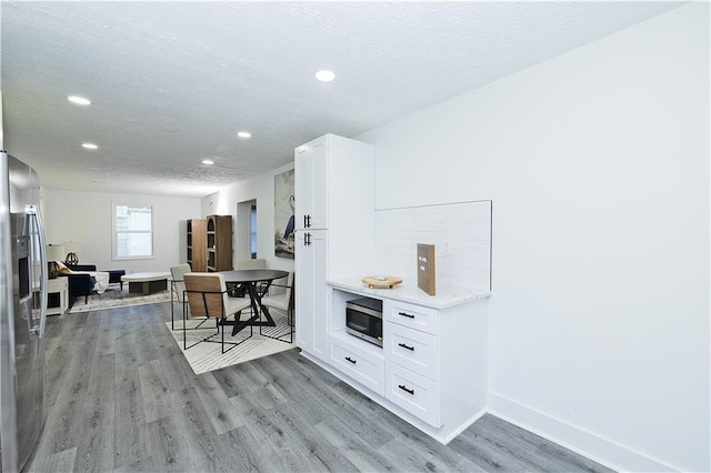 interior space with baseboards, light wood finished floors, and recessed lighting