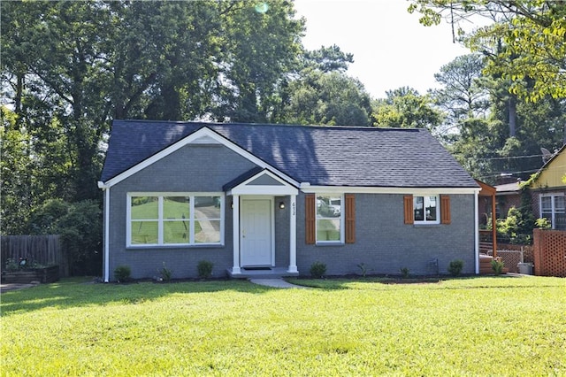 view of front of property with brick siding, fence, and a front yard