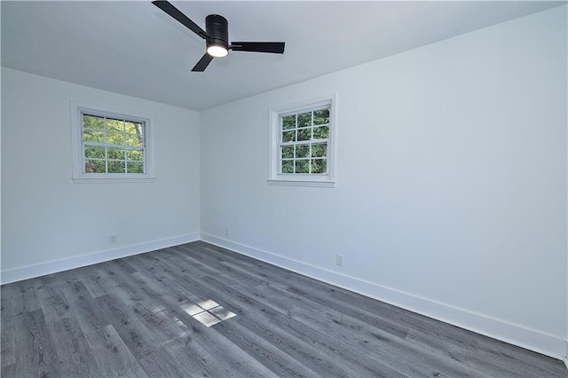 unfurnished room with baseboards, dark wood-type flooring, a ceiling fan, and a healthy amount of sunlight