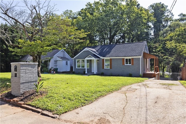 ranch-style house featuring a shingled roof, a front yard, and fence