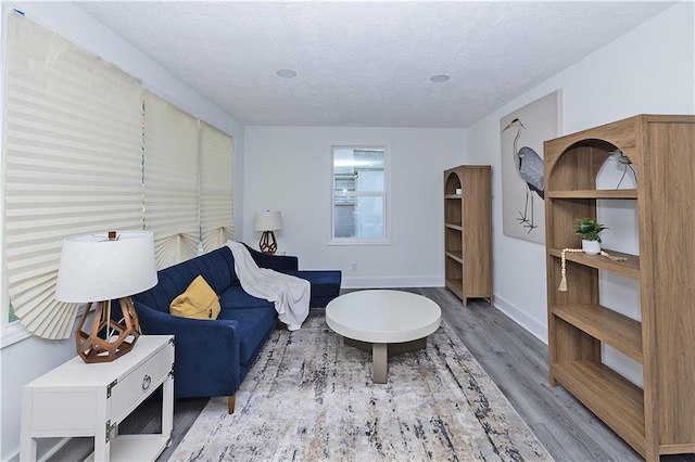 living area with arched walkways, a textured ceiling, baseboards, and wood finished floors