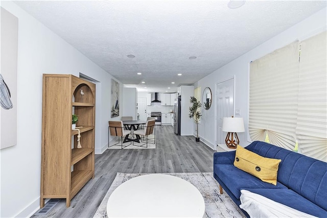 living room featuring baseboards, a textured ceiling, and light wood finished floors