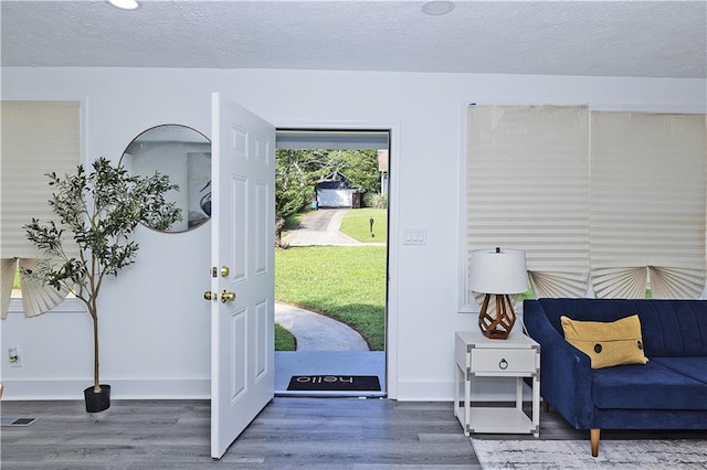 interior space featuring a textured ceiling, wood finished floors, visible vents, and baseboards