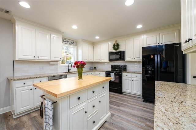 kitchen with wood finished floors, black appliances, butcher block countertops, and a sink