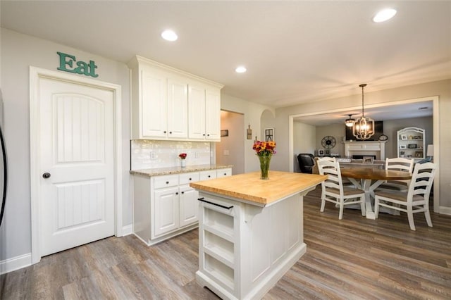 kitchen with butcher block counters, wood finished floors, white cabinets, backsplash, and open shelves