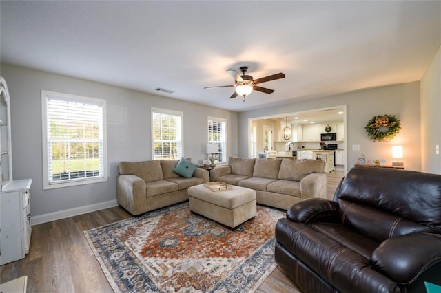 living area featuring ceiling fan, wood finished floors, visible vents, and baseboards