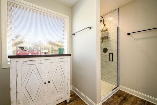 full bathroom with a shower stall, baseboards, and wood finished floors