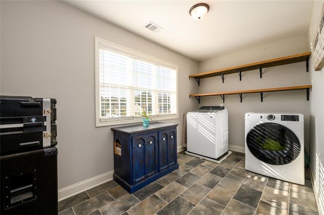 clothes washing area featuring laundry area, visible vents, baseboards, stone finish floor, and separate washer and dryer