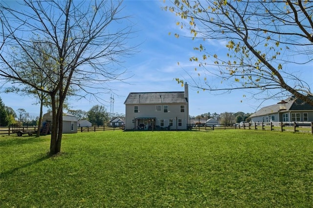 rear view of property with a yard, a chimney, and fence