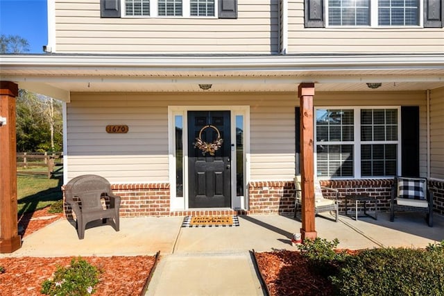 doorway to property featuring a porch and brick siding