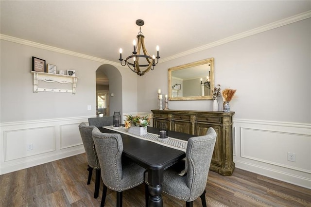 dining area featuring arched walkways, dark wood finished floors, wainscoting, crown molding, and a chandelier