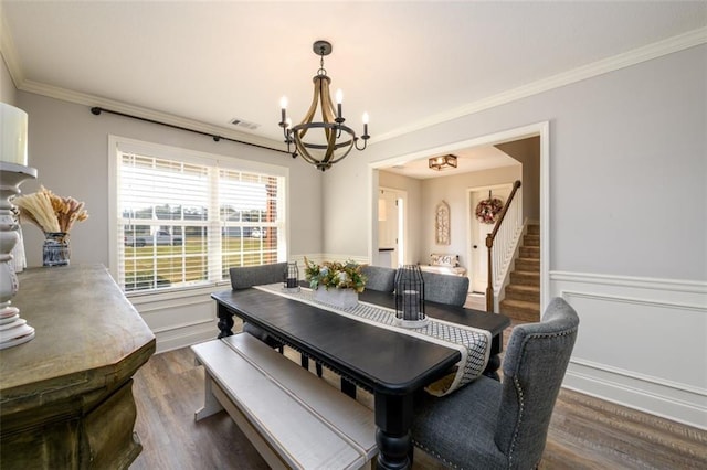 dining area with an inviting chandelier, ornamental molding, dark wood-type flooring, wainscoting, and stairs