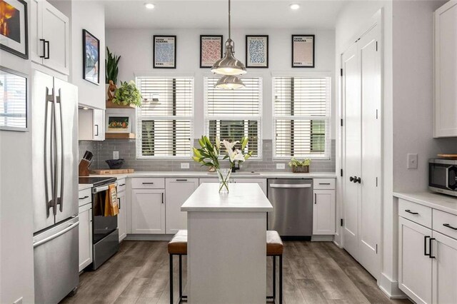 kitchen featuring light countertops, backsplash, stainless steel appliances, and wood finished floors