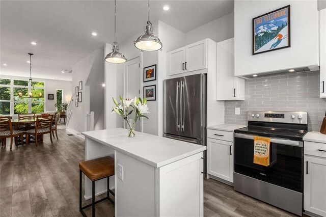 kitchen with light countertops, appliances with stainless steel finishes, decorative backsplash, and a center island