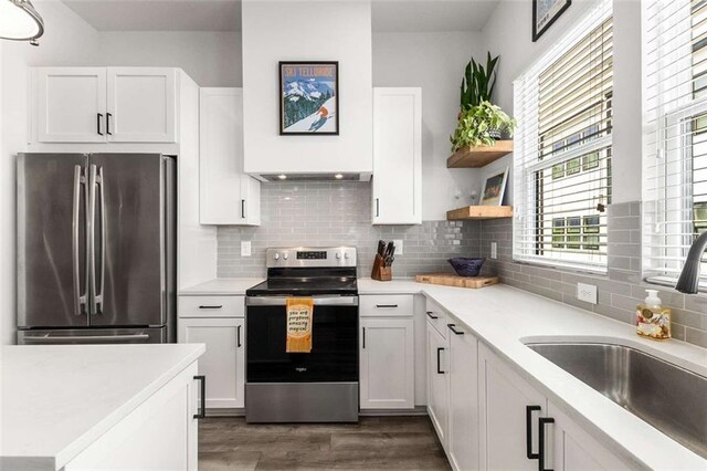 kitchen featuring dark wood-style flooring, light countertops, white cabinets, a sink, and appliances with stainless steel finishes