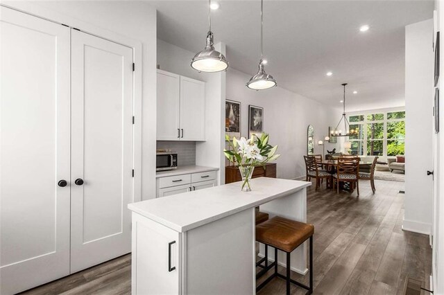 kitchen with light countertops, white cabinetry, stainless steel microwave, recessed lighting, and a kitchen island