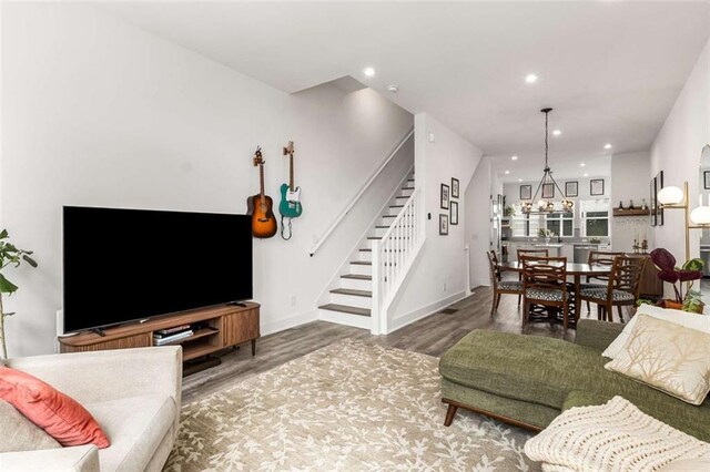 living room featuring an inviting chandelier, recessed lighting, baseboards, wood finished floors, and stairway