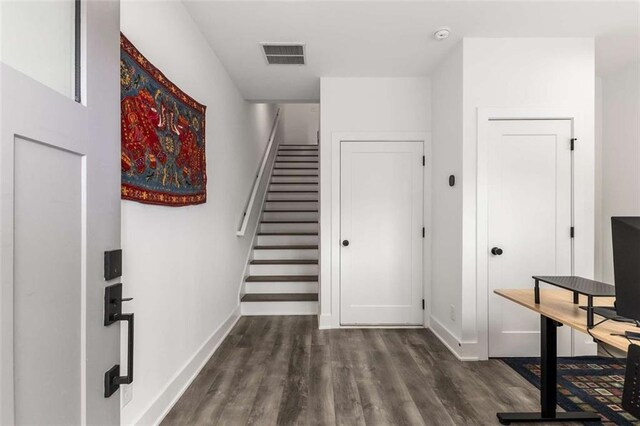 staircase with baseboards, visible vents, and wood finished floors