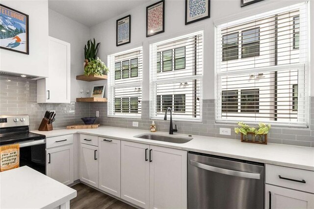 kitchen with backsplash, appliances with stainless steel finishes, a sink, light countertops, and white cabinets