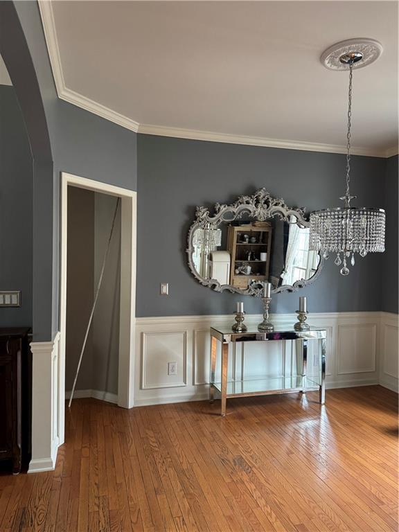 unfurnished dining area featuring crown molding and wood-type flooring