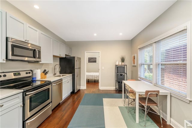 kitchen featuring appliances with stainless steel finishes, dark hardwood / wood-style floors, sink, and white cabinetry