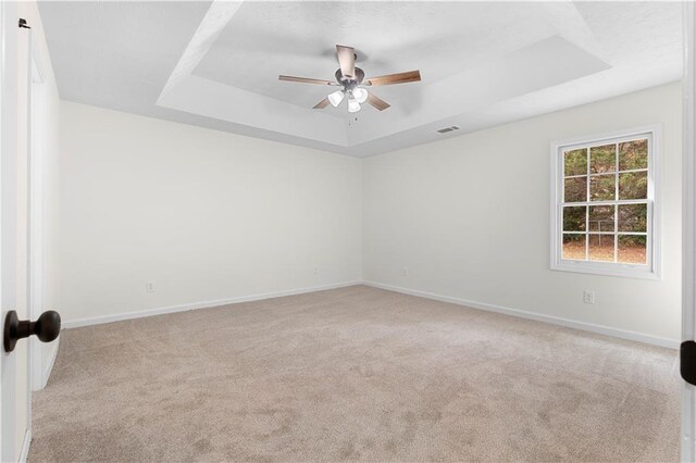 carpeted empty room featuring ceiling fan and a tray ceiling