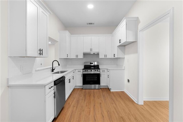 kitchen featuring white cabinets, sink, appliances with stainless steel finishes, and light hardwood / wood-style flooring