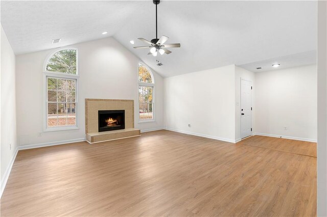 unfurnished living room featuring a fireplace, light wood-type flooring, ceiling fan, and lofted ceiling